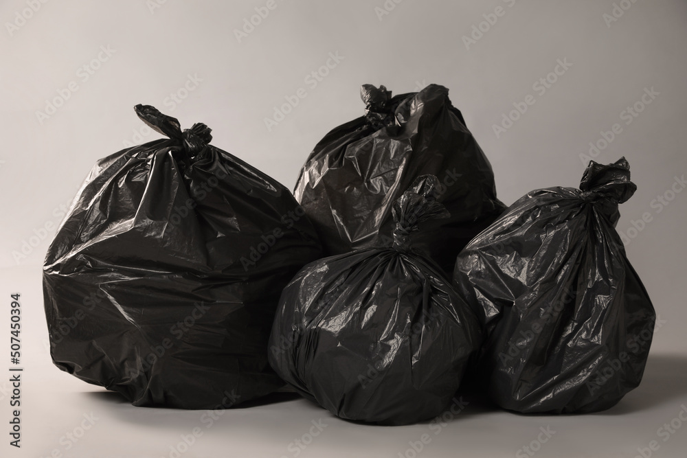 Trash bags full of garbage on grey background