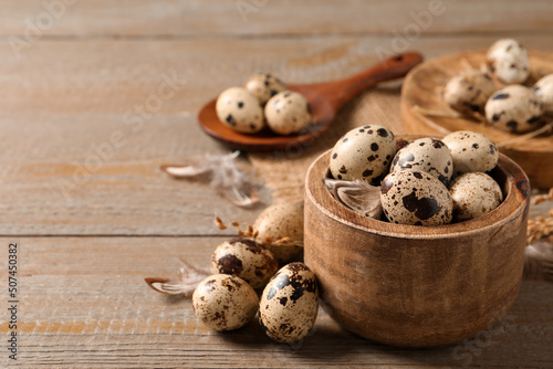 Bowl and quail eggs on wooden table. Space for text