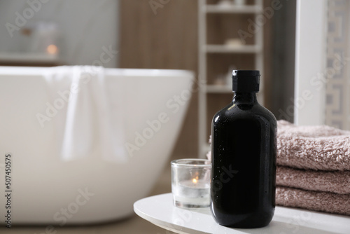 Bottle of shower gel and fresh towels on white table in bathroom. Space for text