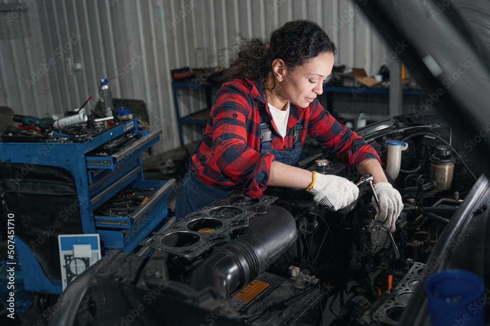 Female auto mechanic repairing car in automobile garage Female auto mechanic repairing car in automobile garage