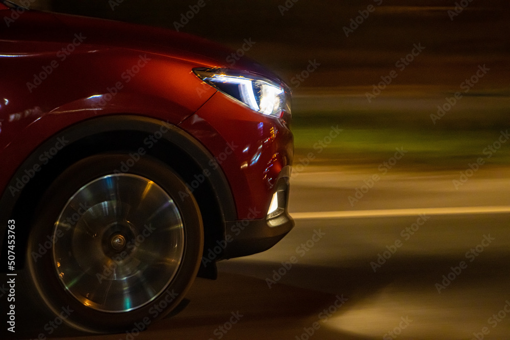 A front part with headlights of a car driving in the night on the road