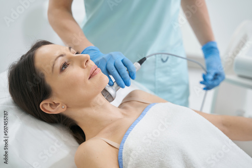 Beauty expert using RF-therapy on female neck