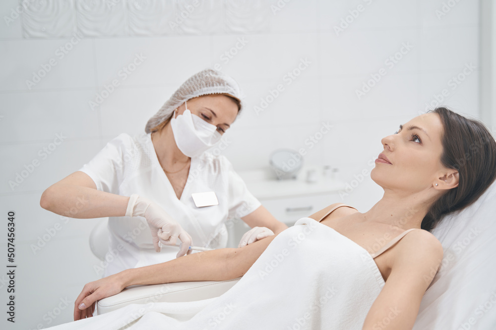 Doctor cosmetologist doing beauty injection into female arm Doctor cosmetologist doing beauty injection into female arm