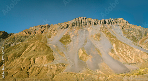 Panoramic view of Himalaya mountains and steep slopes with rock and sand under blue sky. Kaza, India. photo