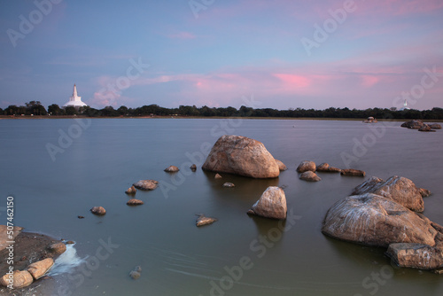 A rock formation in a lake with the beautiful colours of sunset in the background.