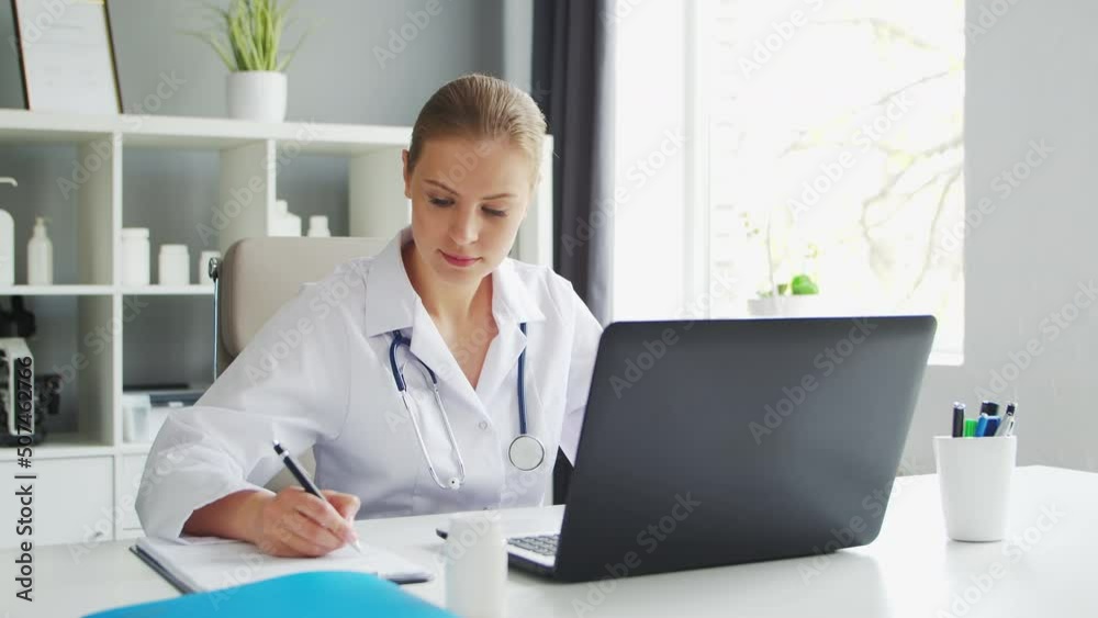 Doctor Works in the Medical Office. Woman in White Coat. Workplace of a Professional Female Therapist in a Hospital or Clinic. Healthcare and Medicine. Doctor Works in the Medical Office. Woman in White Coat. Workplace of a Professional Female Therapist in a Hospital or Clinic. Healthcare and Medicine.