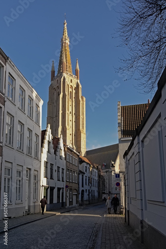 Tower of the church of our Lady above a street with medieval houses in Bruges