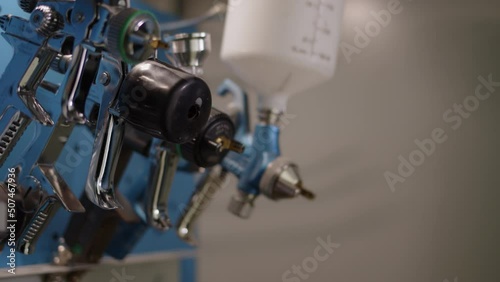 Close up rack focus four spray guns in cabinet. High-precision airbrushes hang next to spray booth for work. concept of painting car bodies or any other equipment. photo