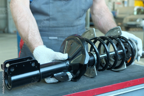 Car service. The suspension of the car. An auto mechanic prepares a new shock absorber rack for installation during repair and maintenance of the car. photo