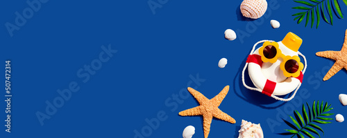 Sunblock bottle wearing sunglasses with starfish and seashells - flat lay