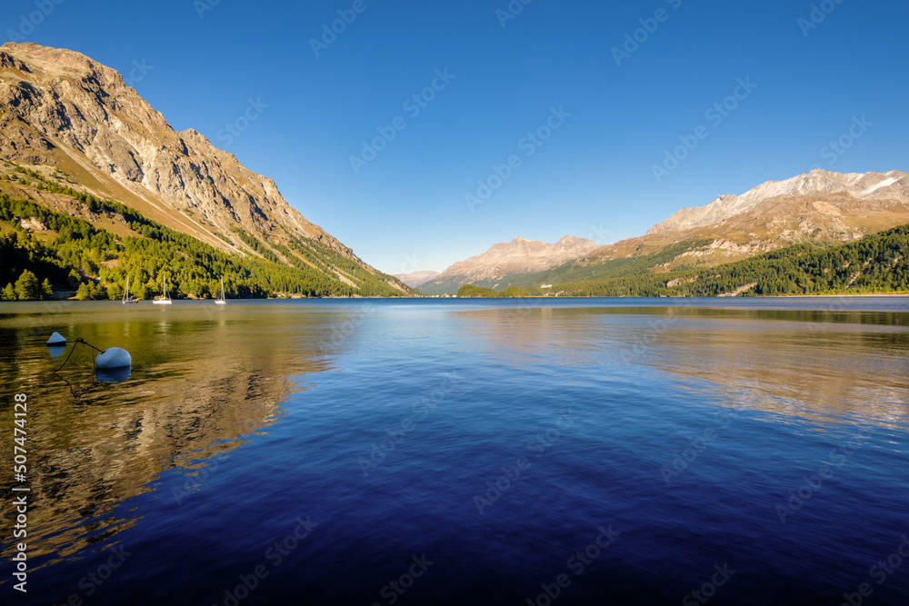 September sun is setting at gorgeous Plaun da Lej, a famous Swiss bay at Lake Sils (Silsersee), in the Upper Engadine Valley (Grisons, Switzerland). It lies between Lake Silvaplana and Maloja Pass