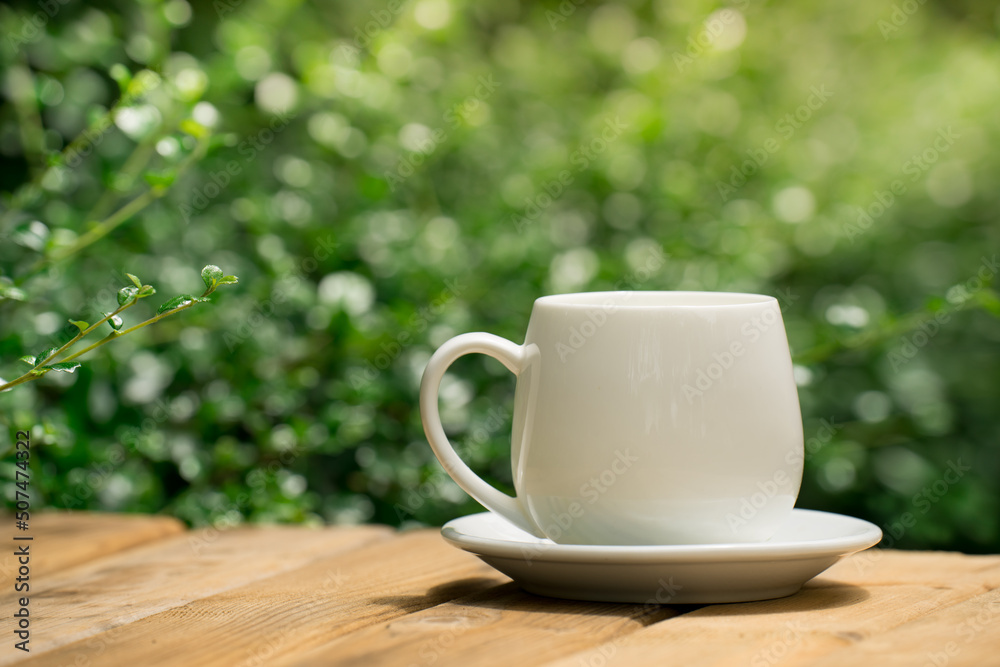white ceramic coffee mug On the wooden floor, green tree bokeh background. white ceramic coffee mug On the wooden floor, green tree bokeh background.