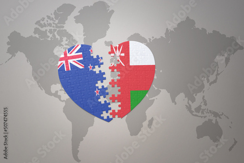 puzzle heart with the national flag of new zealand and oman on a world map background. Concept.