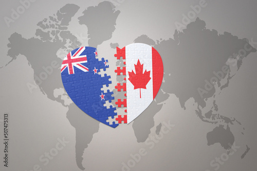 puzzle heart with the national flag of new zealand and canada on a world map background. Concept.