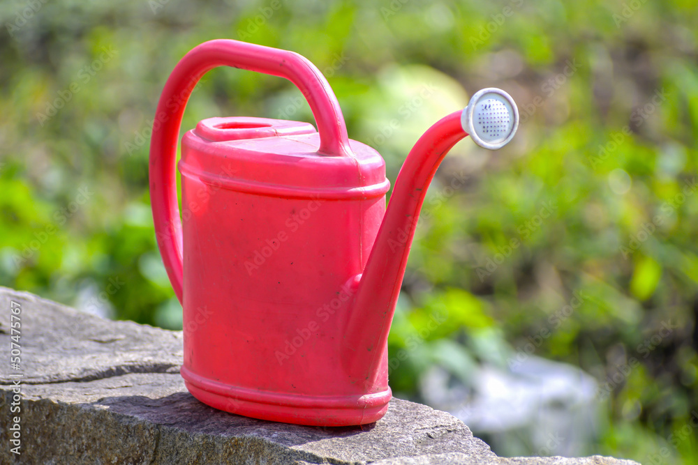 Garden watering can on a stone wall close-up