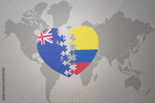 puzzle heart with the national flag of new zealand and colombia on a world map background. Concept.
