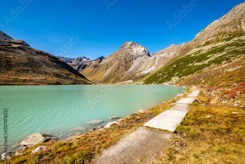 Walking along the largest lake in the Ötztal Alps, beautiful Lake Rifflsee. It is located close to the Kaunergrat Nature Park above the Pitztal Valley, surrounded by Ötztal Alps and Kaunergrat peaks.