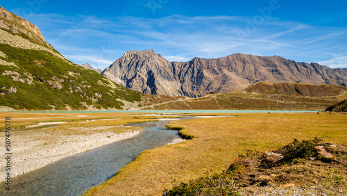 Walking along the largest lake in the Ötztal Alps, beautiful Lake Rifflsee. It is located close to the Kaunergrat Nature Park above the Pitztal Valley, surrounded by Ötztal Alps and Kaunergrat peaks. photo