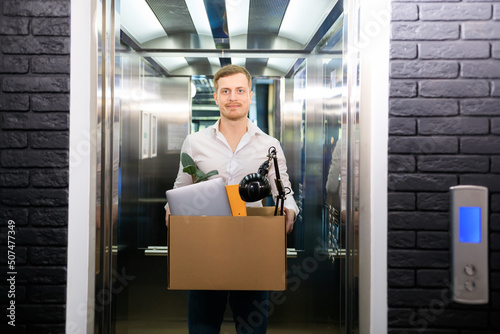 Wallpaper Mural A young man holds a box with his stuff in an office elevator Torontodigital.ca