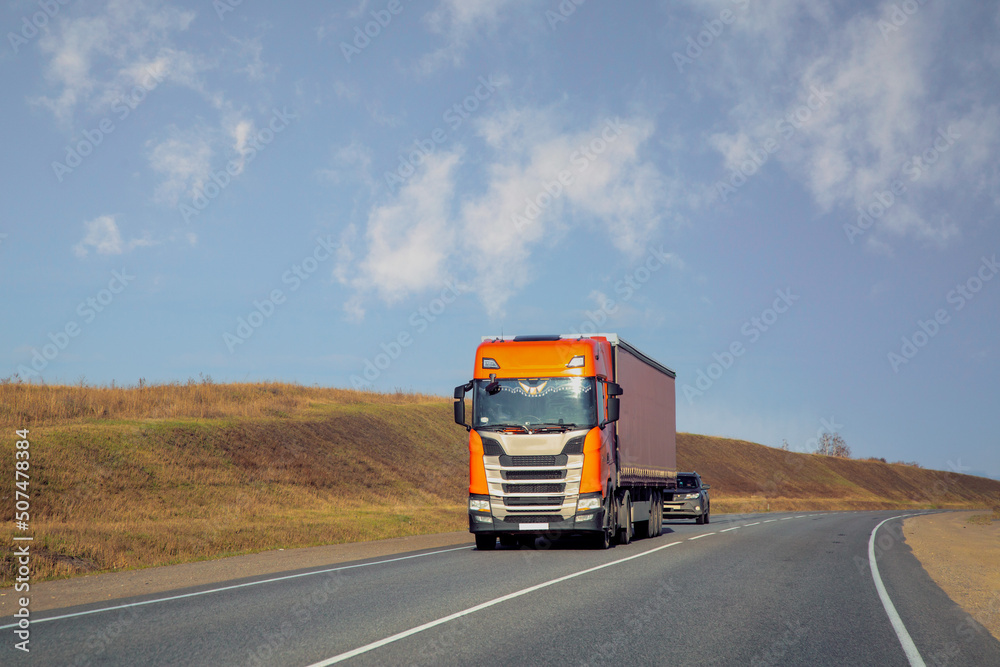 The truck is moving along a suburban highway. Cargo transportation, logistics.