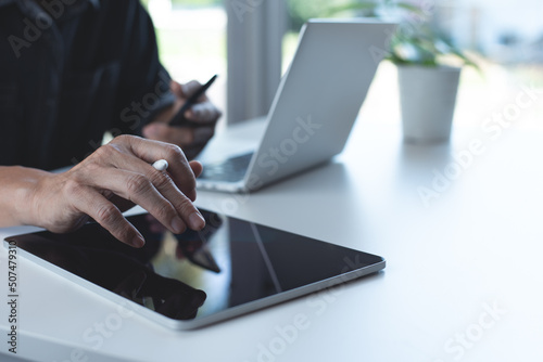Business man using digital tablet and working on laptop computer with mobile phone on table at home office. Working at home, telecommuting, e-learning