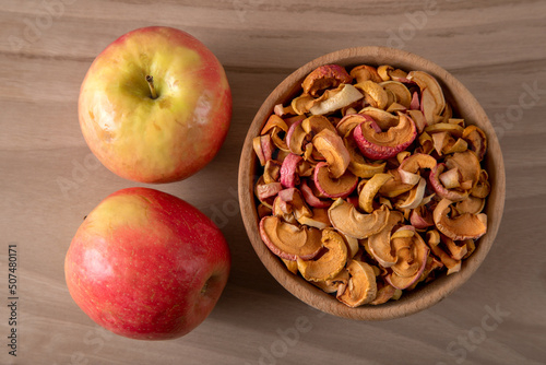 Dried apple slices and fresh apples on wooden background