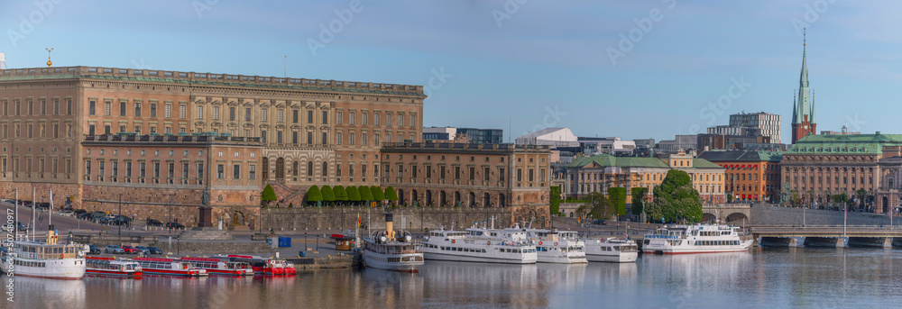Pier with commuter boats and tourist boats at the slope Slottsbacken, the castle and the old town Gamla Stan a sunny summer day in Stockholm