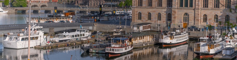 Panorama view over service piers at the bridge between the island Skeppsholmen and Blasieholmen, steam commuting boats a sunny summer day in Stockholm