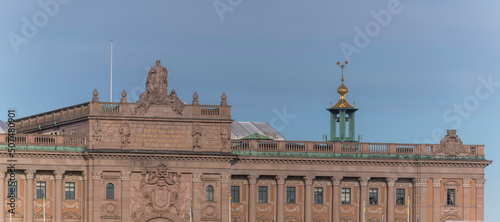 Fa  ade and roof of the parliament building with the spire of the Town City Hall in the background a sunny summer day in Stockholm