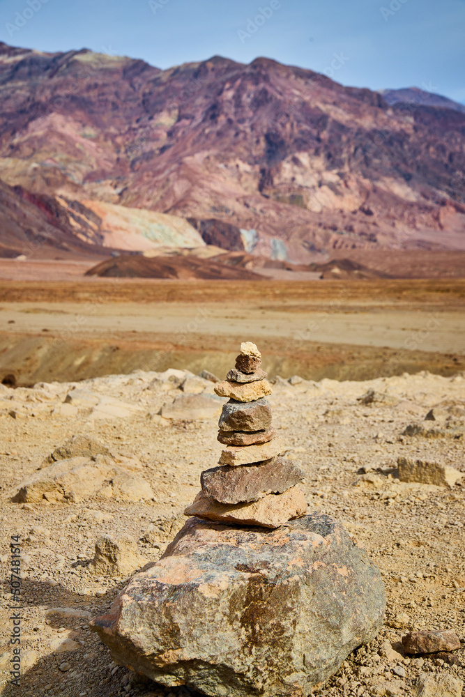 Cairn stack of rocks in Death Valley by layers of colorful mountains