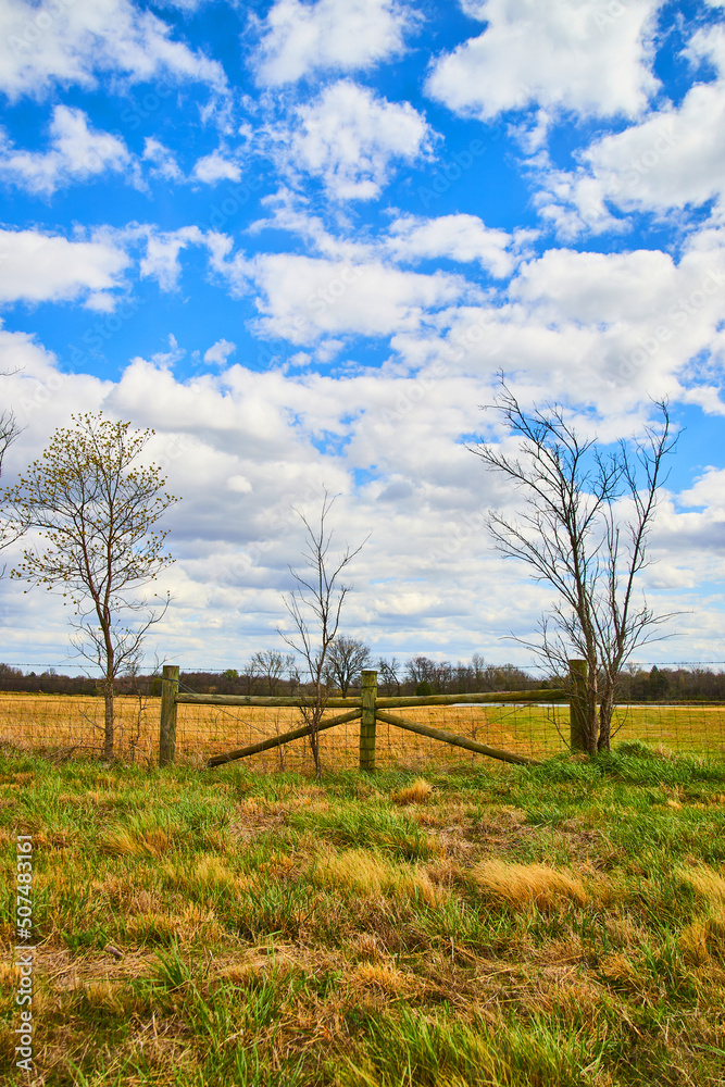Fluffy clouds and blue sky over farmland fencing