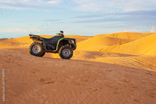 Quadracycle stands among the yellow sand dunes in the Sahara desert under the blue sky in Tunisia. Desert quad bike racing. Travel landscape with copy space © Вера Тихонова