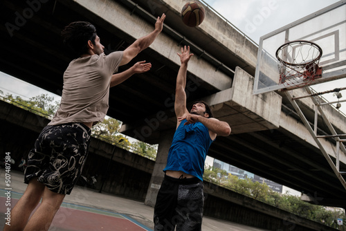 Two caucasian men pratice baskegball in court at urban street. photo