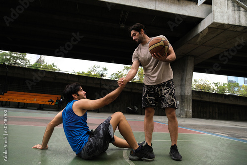 Two caucasian men pratice baskegball in court at urban street. photo