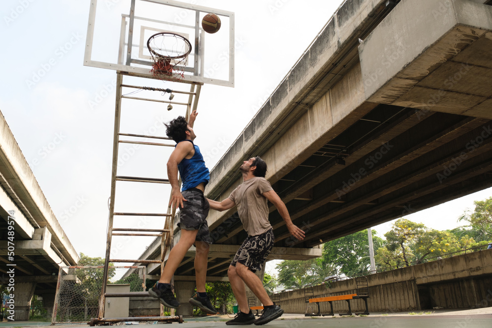 Two caucasian men pratice baskegball in court at urban street. Two caucasian men pratice baskegball in court at urban street.