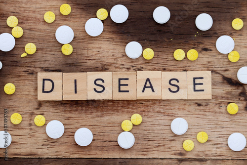 wooden block with the word diasease written on it with a wooden backdrop and medicine photo