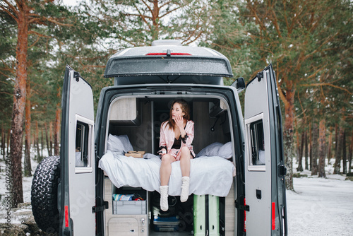 Fotografi Young woman inside her campervan in winter relaxing and looking outdoors
