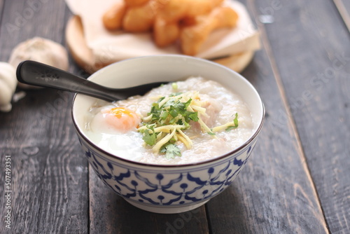 Congee in a Thai-patterned cup and fried batter served in an Asian-style cup on a black table with fried batter that we call 
