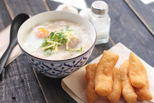 Joke or Congee in a Thai style cup Served on a black wooden table. It's an Asian breakfast.