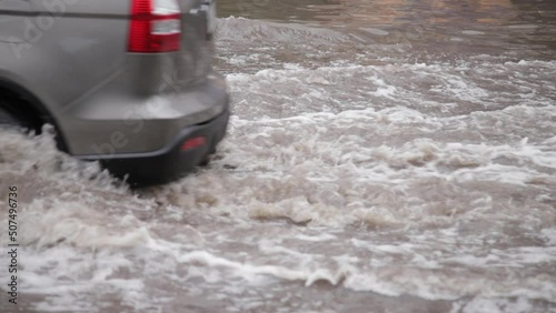 Town street flooded by heavy rain. Thunderstorm consequences. Car floating in puddles. Climate changes, adverse weather conditions, ecological traffic problem