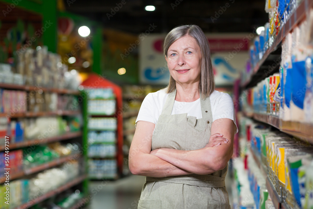 Portrait of happy senior woman grocery store employee with arms crossed smiling and looking at camera