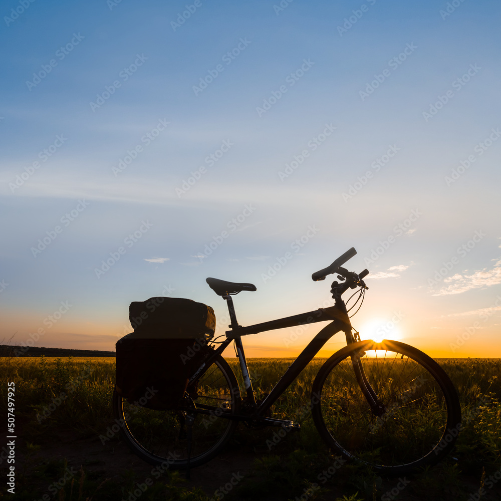 bicycle silhouette in prairie at the dramatic sunset, outdoor travel sport scene