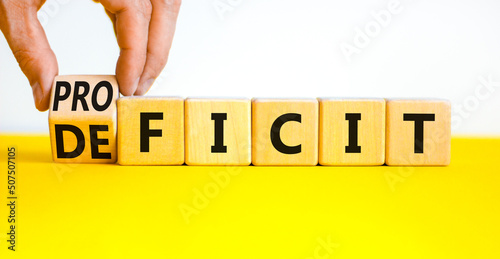 Proficit or deficit symbol. Businessman turns wooden cubes and changes the concept word deficit to proficit. Beautiful yellow table white background. Business proficit or deficit concept. Copy space. photo