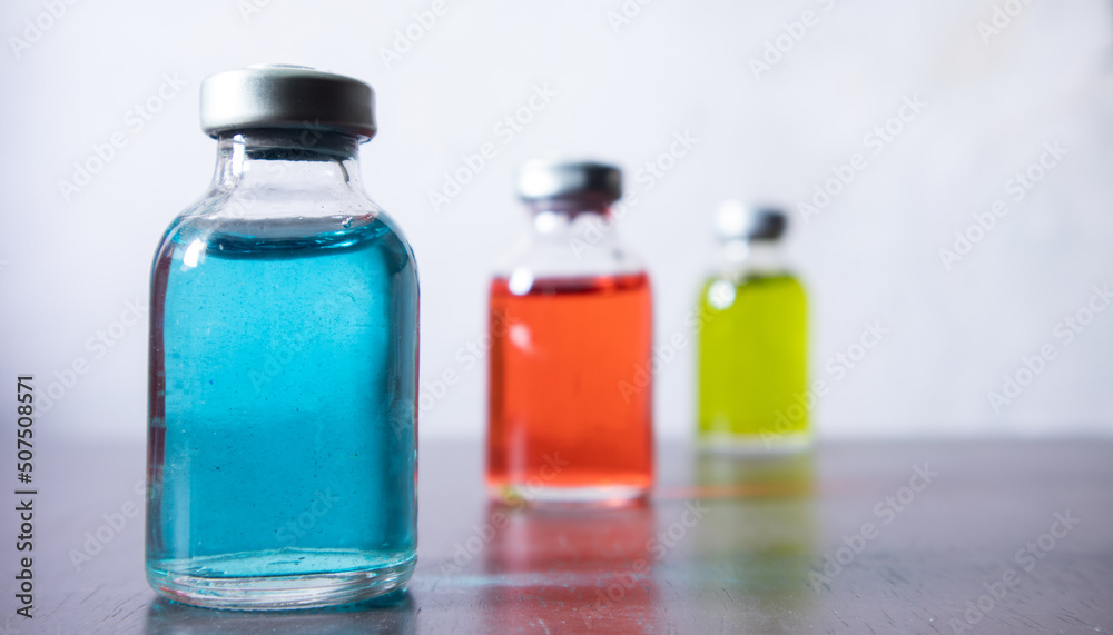 Medical reagent in the sterile vial that contained red, green, and blue solution. some vial contain particulate matter. the defection of pharmaceutical production. focusing at the left Medical reagent in the sterile vial that contained red, green, and blue solution. some vial contain particulate matter. the defection of pharmaceutical production. focusing at the left