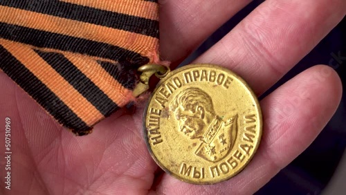 Soviet medals in hands. Victory in WWII. The victory of the Russian people. Image of Stalin. Reward for victory. Gold. Close-up. The symbol of victory. St. George Ribbon. photo