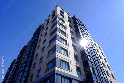 A high-rise building, an apartment building from below on a blue sky background.Newly built multi-storey house. Construction of a residential complex.Urban landscape.