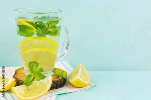 Lemon drink with mint in a tall glass glass with a handle on a blue background. Space for text. Detox, fruit water, lemonade, vitamin C, proper nutrition.
