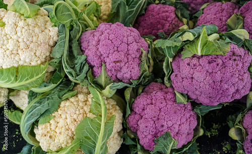 Vibrant organic cauliflower in white and purple varieties, fresh from the field, displayed at a farmers market stall, natural and healthy food in two colors