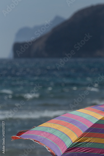 Multi coloured parasol against the background of sea and coastal shoreline © Mark