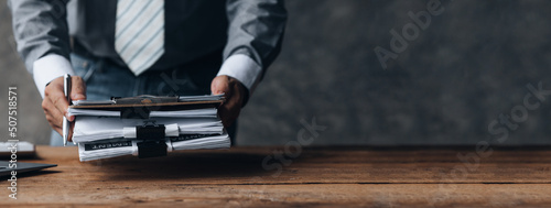 Businessman holding a pile of company financial documents, he is checking company finances before attending a meeting with the finance department. Concept of corporate financial management. photo
